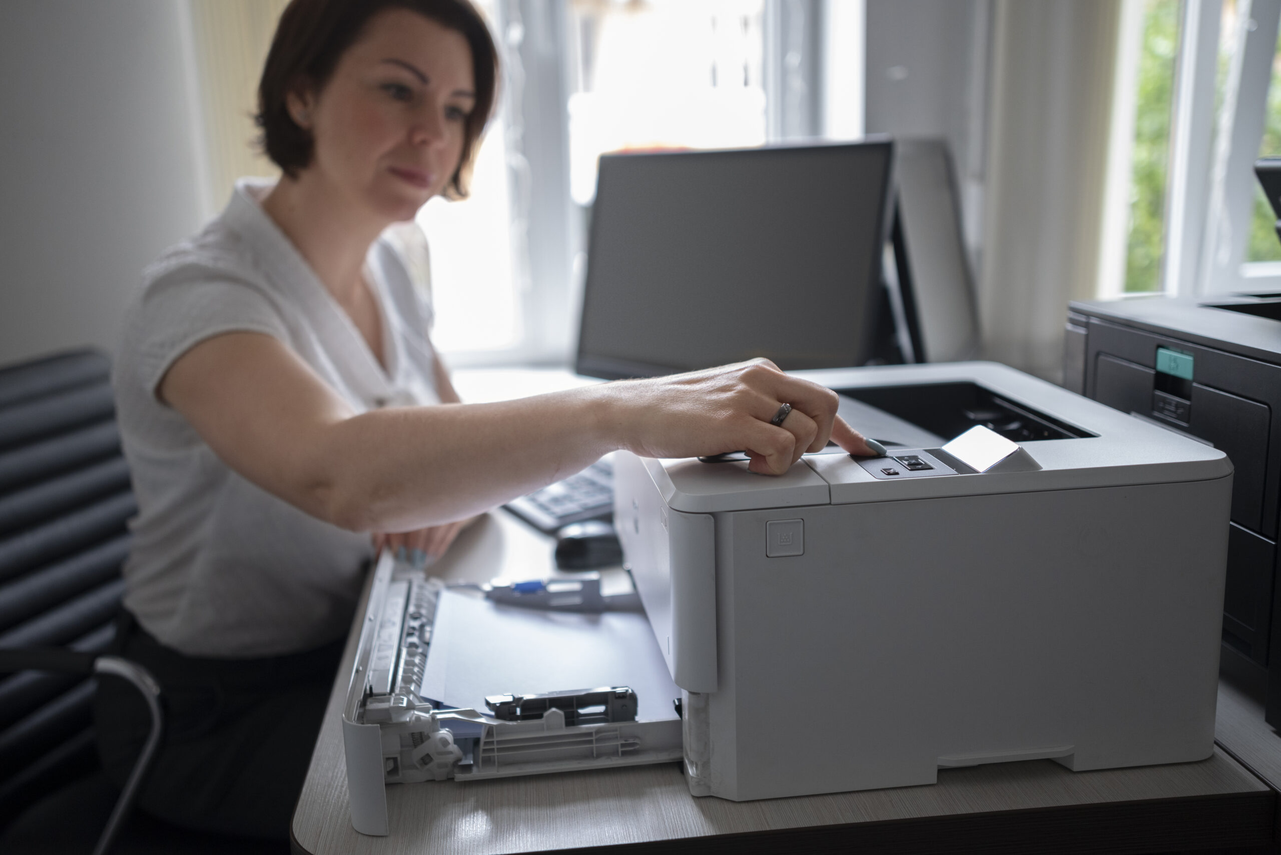 Close-up of hands loading paper into an office printer